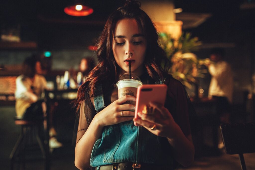 カフェでコーヒーを飲みながらスマホを見る女性