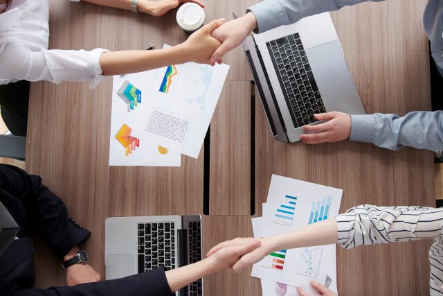 握手を交わす手とPC