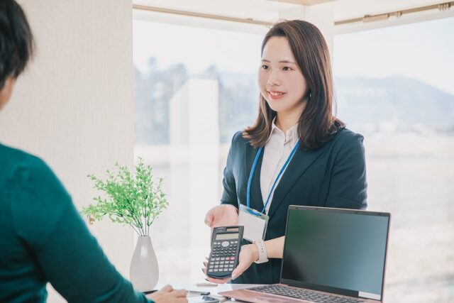 金額を計算機で顧客に見せている女性