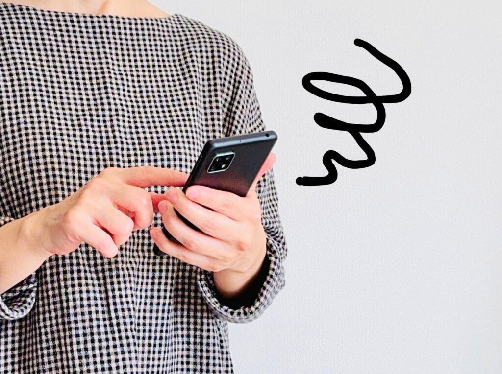 SNS運用に悩む女性マーケターがスマートフォンを見つめるイメージ